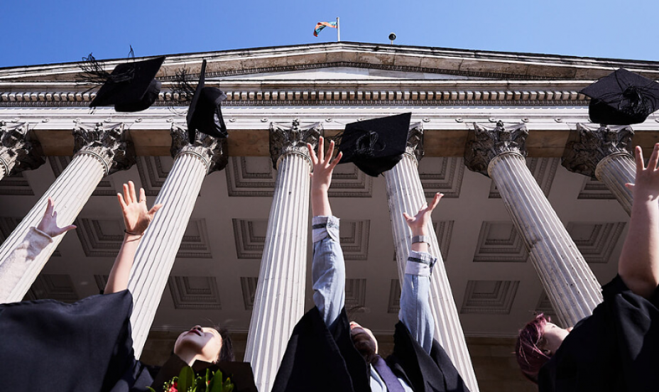 С̳ Graduates through caps into the air. 